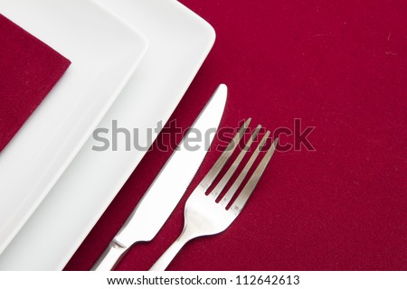 Red tablecloth with white square plates and red napkin