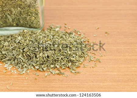 Pile of dried parsley with jar on wooden worktop