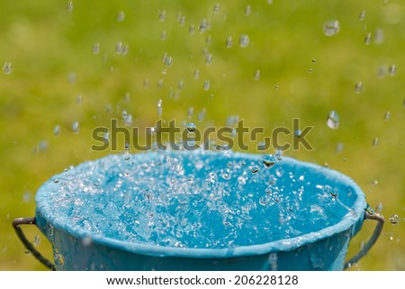 Rain falling into a full bucket of water