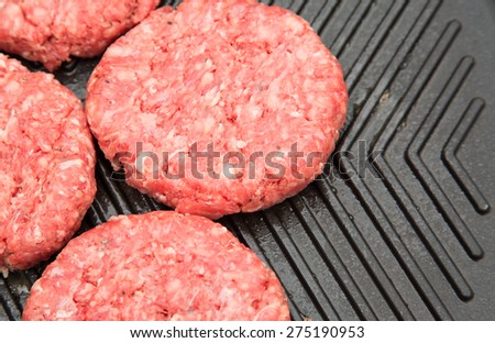 Raw burgers on a metal grriddle