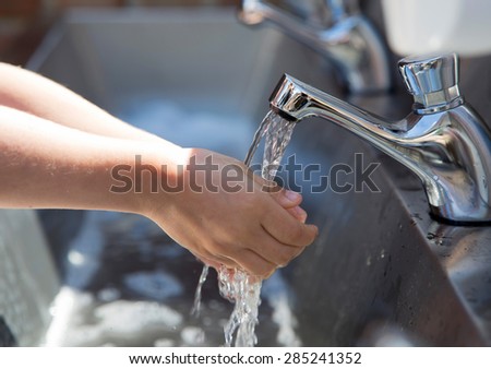 Child washing hands in a steel basin