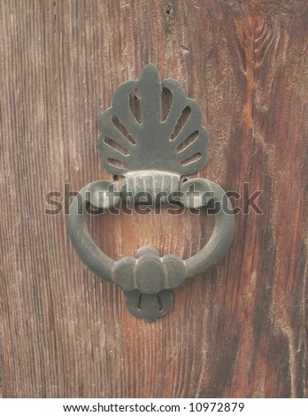 A vintage cast iron door knocker on a solid wood door