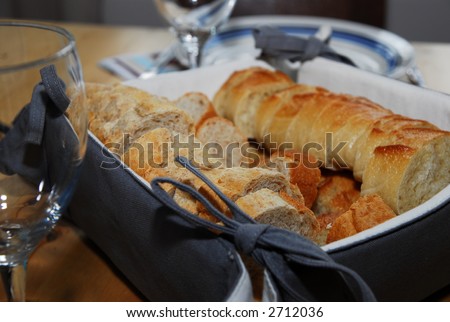Covered table with wine glasses, plates, and French bread products