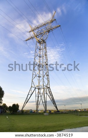 Electricity pylon and power lines against blue sky with clouds. Rural environment.