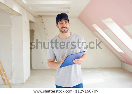 Young renovation worker holding clipboard in his hand while standing at constrcution site.