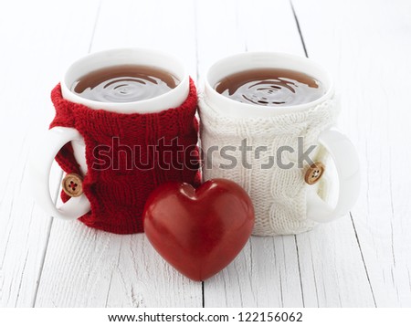 Two warm cups of tea with red and white knitted thing on it and with heart for Valentine\'s day