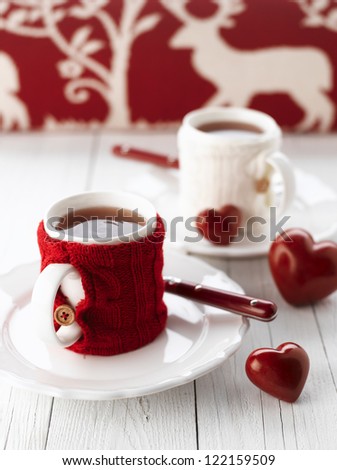 Two warm cups of tea with red and white knitted thing on it and with heart for Valentine's day