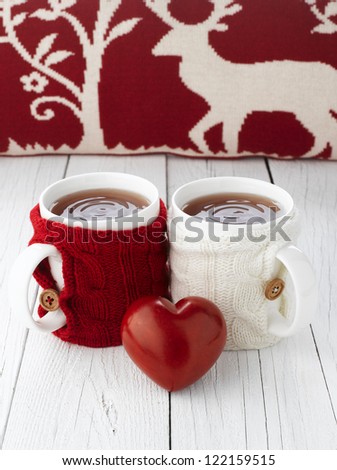 Two warm cups of tea with red and white knitted thing on it and with heart for Valentine\'s day