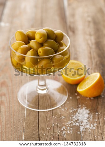 Bowl of olives with lemon and salt on wooden table. Shallow Focus, vibrant color.