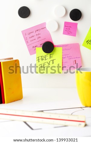 Office work area. Desk with pink and yellow 'Post It' notes.