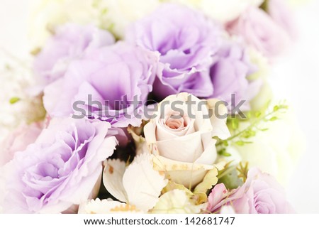 Professionally prepared decorative spring flower arrangement on reception wedding table. Shallow focus, white linen background.