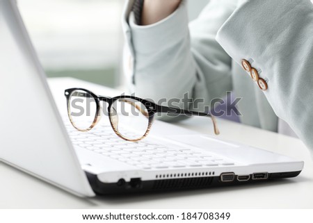 Close-up of businesswoman sitting at desk behind the laptop.