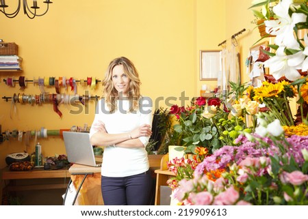 Beautiful florist standing in front of flower shop facade. Small business.