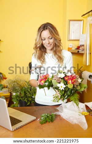 Portrait of middle age flower shop owner standing at desk,  while holding a bunch of flower.