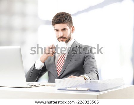 Close-up portrait of sales man working on laptop while drinking coffee at office.