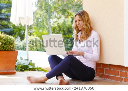 Portrait of happy blogger writing her blog at laptop while sitting at garden at home.