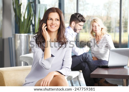 Portrait of mature sales woman smiling during a telephone conversation while sitting at meeting.