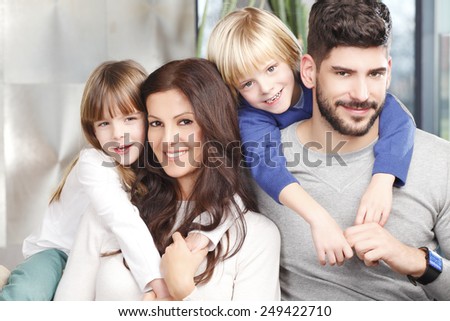 Portrait of happy family with two kids sitting at sofa at living room.