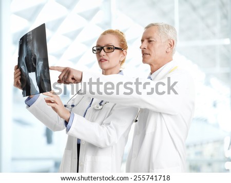 Male doctor shows the problem areas on a X-ray to his colleagues at private clinic.