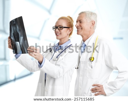Female doctor holding x-ray image and consulting with male doctor at hospital.