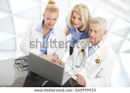 Portrait of medical team sitting at desk in front of computer and consulting. Medical group.