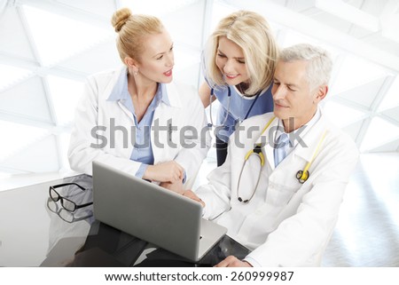 Portrait of medical team sitting at desk in front of computer and consulting. Medical group.