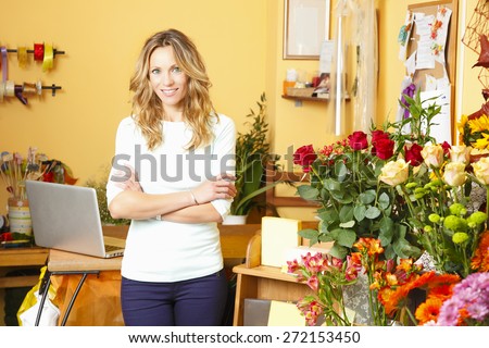 Small business. Portrait of friendly small flower shop owner standing in front of counter. Looking at camera and smiling.