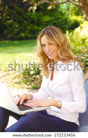 Mature woman portrait. Busy middle age businesswoman sitting at garden at home while working on her laptop.