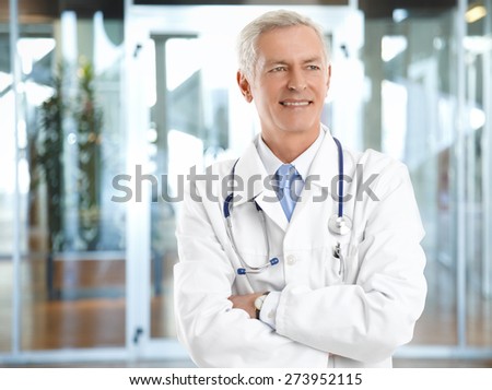 Portrait of confident male doctor with arms crossed standing at hospital.