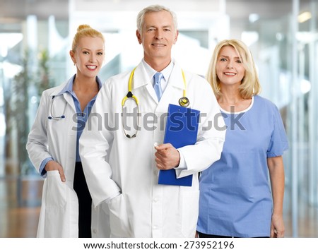 Image of successful healthcare worker at hospital. Portrait of medical assistant standing next to mature female doctor and senior doctor.