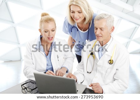 Image of medical staff consulting while sitting at desk in front of laptop at private clinic. Doctors and nurse analyzing the result of medical tests.