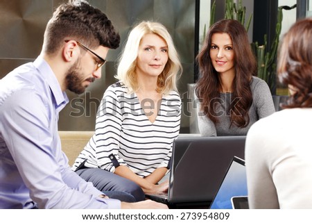 Portrait of sales team sitting at office and working with laptop on financial project. Mature businesswomen looking at camera and smiling.