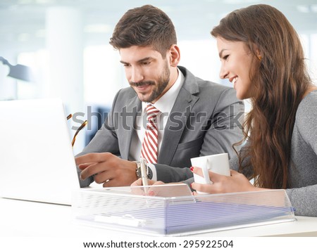 Portrait of two young professionals sitting in front of computer and consulting. Business people working together on next project.