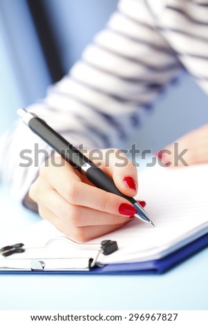 Close-up portrait of young businesswoman sitting at desk and filling IQ test while sitting at desk.
