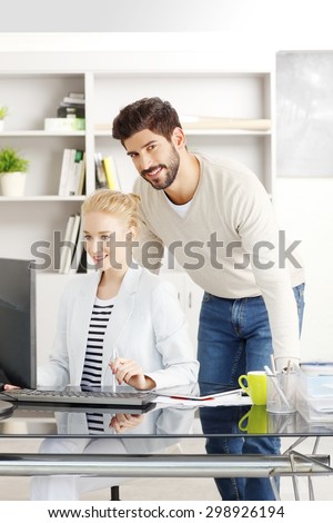 Portrait of young creative working on new project. Female professional sitting at desk and working together with businessman on computer.
