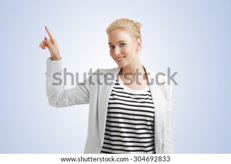Portrait of young woman points out something while standing at isolated background.