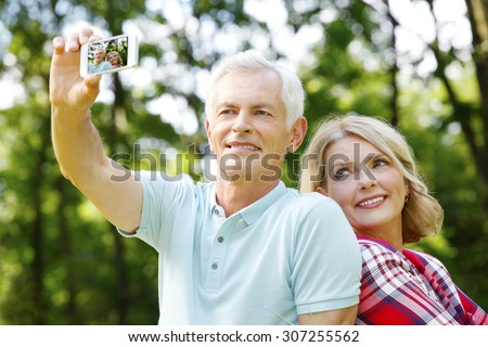 Elderly couple making a self portrait while taking an excursion in the forest