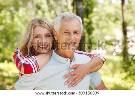 Portrait of senior couple hiking in the forest. Elderly woman embracing her senior man while standing outdoors and spending time together.