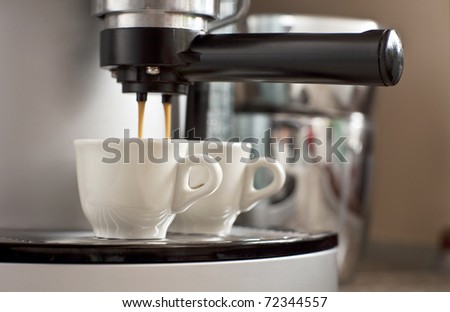 Two cups of espresso being poured from an espresso machine