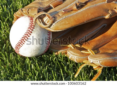 A baseball sits in a mitt on a grass baseball field.