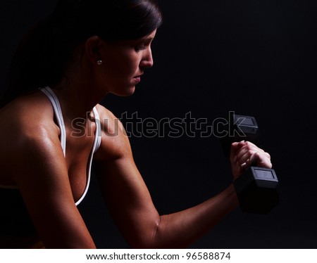 Fitness woman lifting fee weights set against a dark background