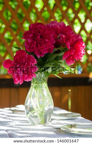 bouquet of peonies in a glass vase standing on a table