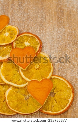 slices of dried orange peel and hearts of on a wooden background