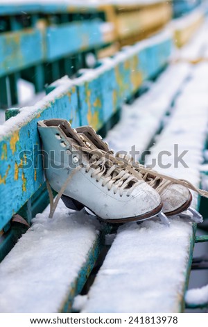 Old skates for figure skating on a wooden bench
