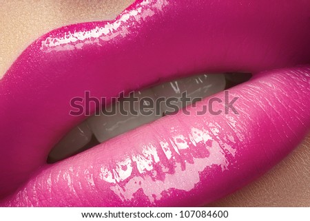 Close-up of woman\'s lips with bright fashion pink glossy makeup. Macro magenta lipgloss make-up