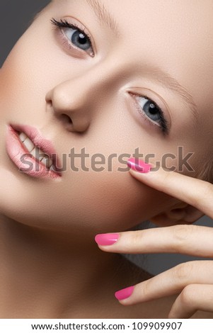 Beautiful young model with natural make-up and bright pink manicure. Wellness. Close-up beauty portrait of lovely european woman with clean healthy skin, pale lips, vibrance nail polish. Spa look