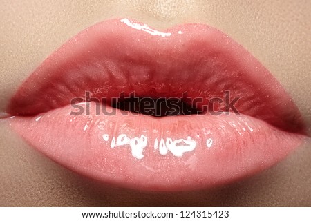 Cosmetics and makeup. Closeup shoot of beautiful lips of woman with pink lipstick and gloss. Sexy wet lip make-up. Sweet kiss. Close-up of beautiful full lips