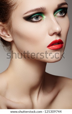 Closeup beauty portrait of attractive model face with bright visage. Green eye makeup and red lips make-up. Evening winter style with red lips