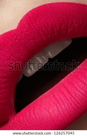 Close-up of beautiful full woman\'s lips with bright fashion mat pink makeup. Vertical macro shot with magenta frosted lip make-up
