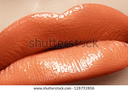 Close-up of woman\'s lips with bright fashion peach lipstick makeup. Horizontal macro coral lipgloss make-up